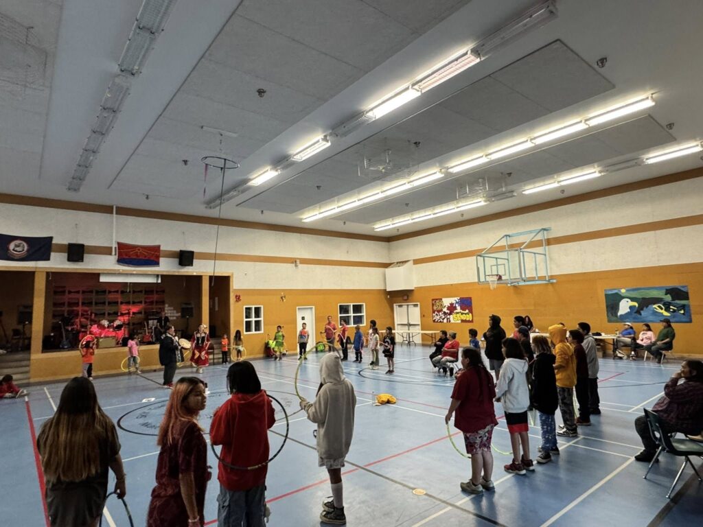 Children participate in a hoop dancing workshop in a gymnasium