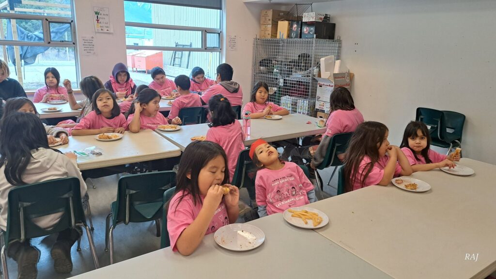 Children wearing pink shirts enjoy a meal together in a bright