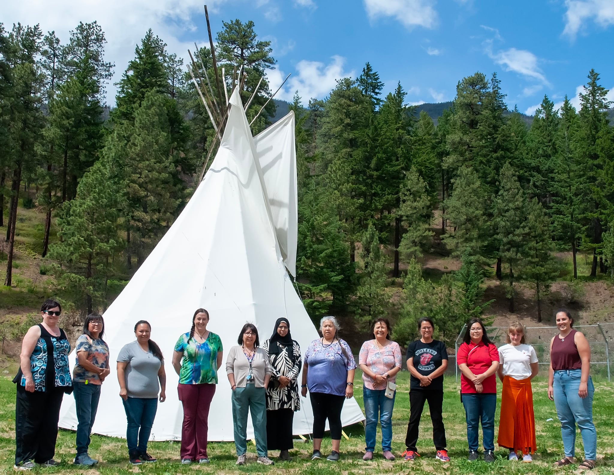 Group of diverse women stand together in front of a teepee